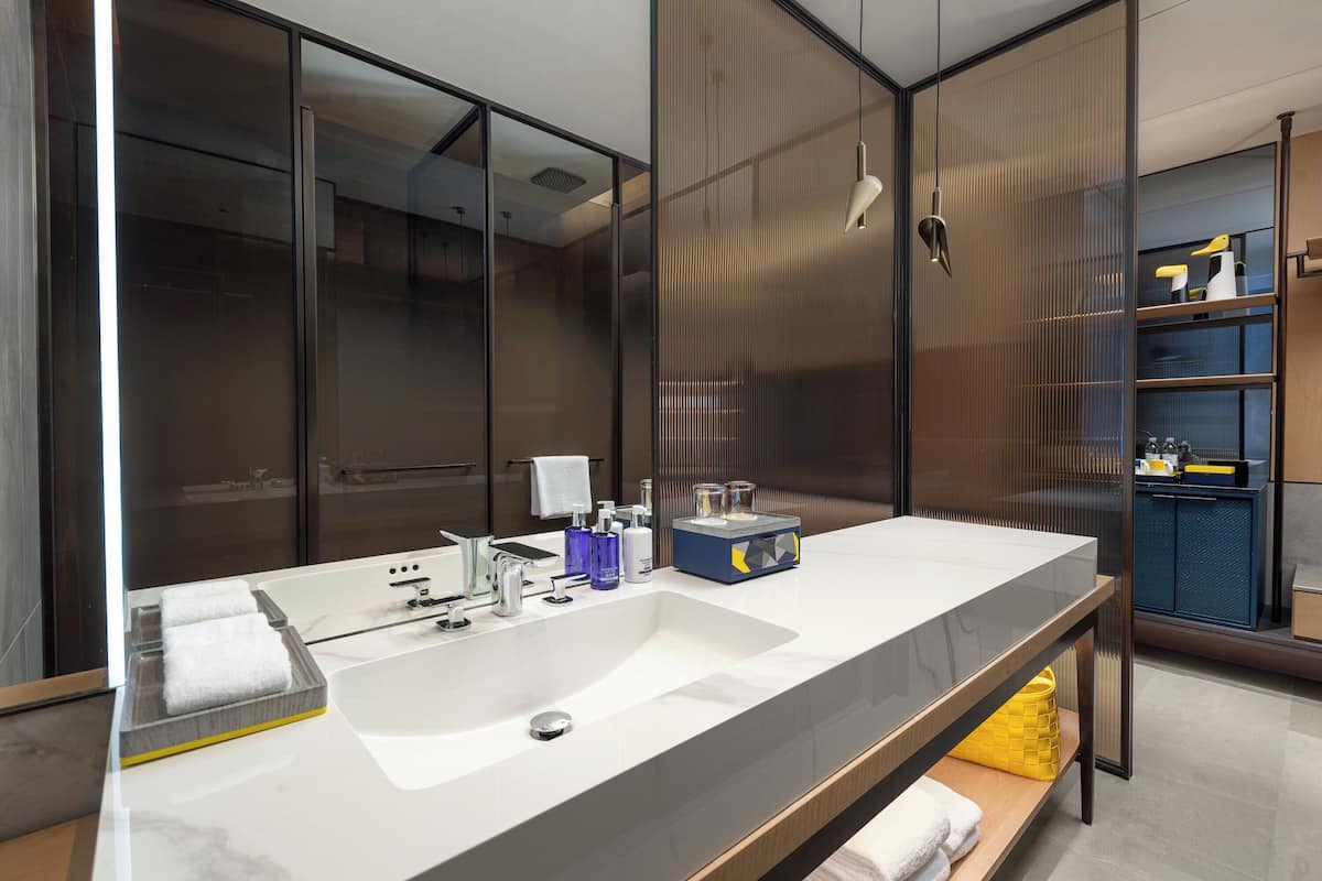 Un baño moderno con un espejo grande, un lavamanos blanco y un mueble de tocador de madera.