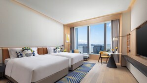 Une chambre d’hôtel moderne avec deux lits, un coin repas et une grande télévision.
