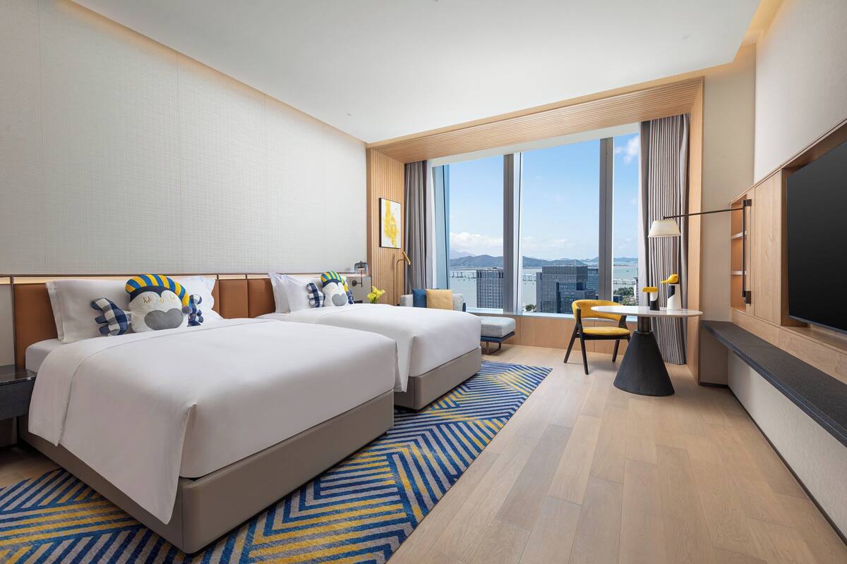 Una habitación de hotel moderna con dos camas, un área de comedor y un televisor grande.