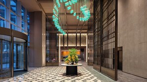 Un hall d’entrée spacieux, doté d’un sol à motifs, d’une table centrale agrémentée de plantes et d’un luminaire au plafond au design original.