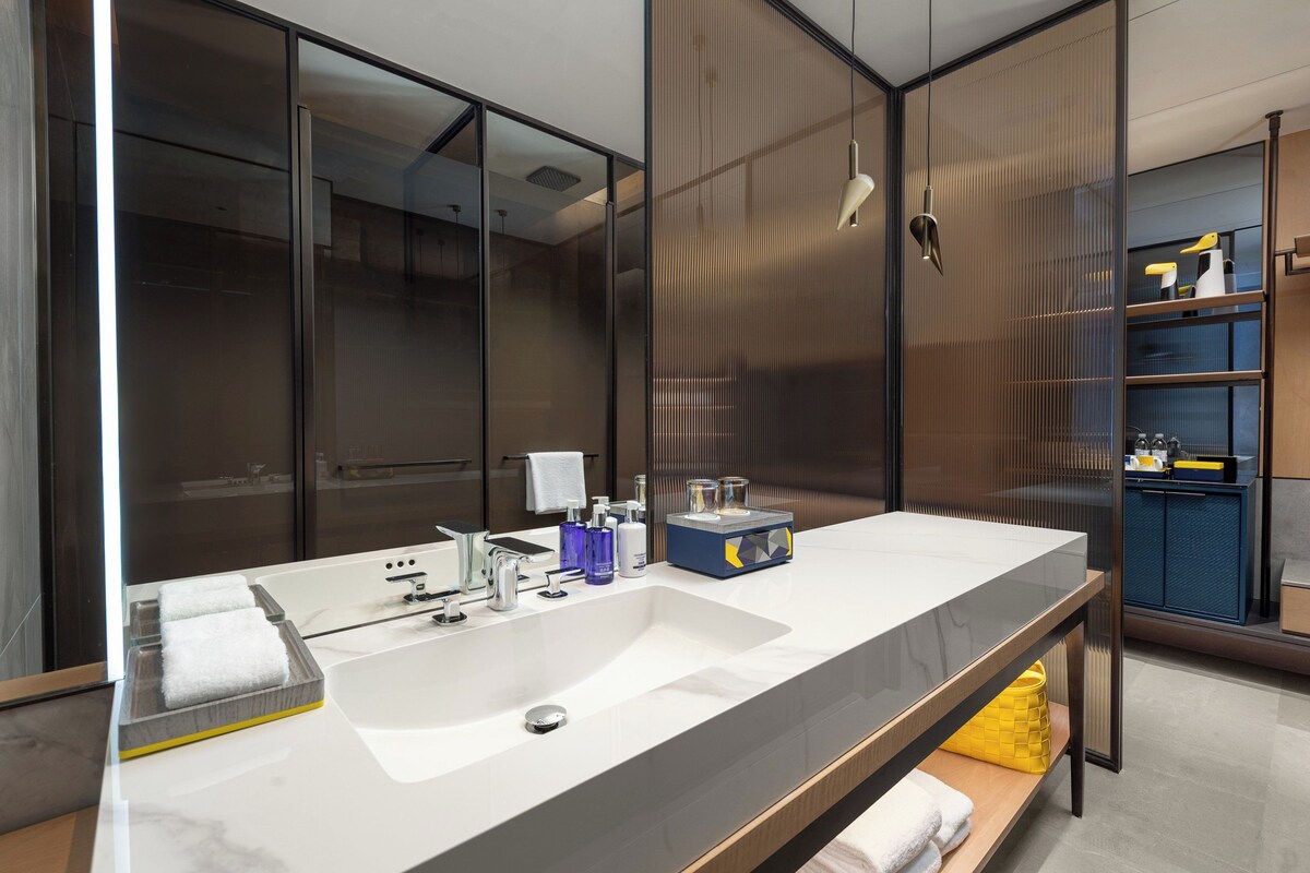 Un bagno moderno con uno specchio grande, un lavandino bianco e un mobile bagno in legno.