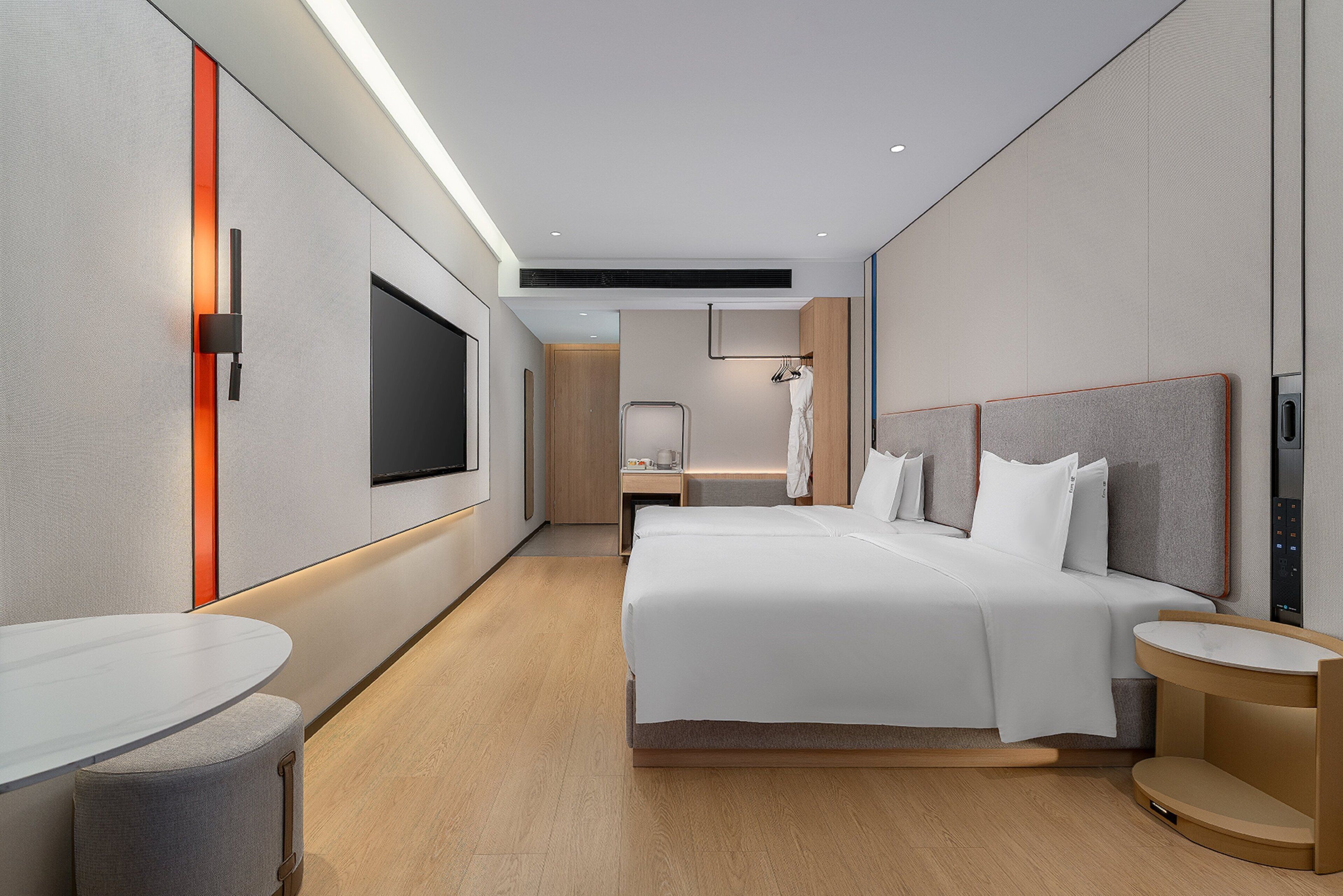Una habitación de hotel moderna con una cama grande, mesitas de noche, televisión y zona de estar.