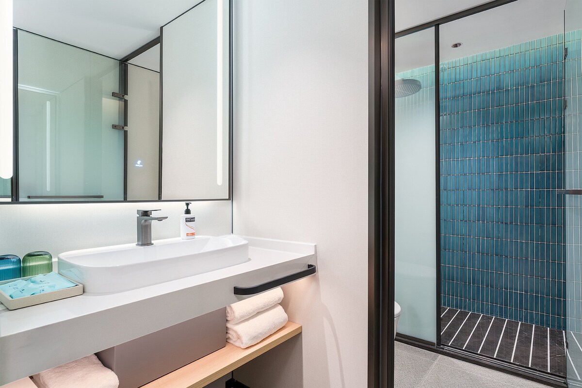 Een moderne badkamer met een wit wastafelmeubel, spiegel en een douchecabine van glas.