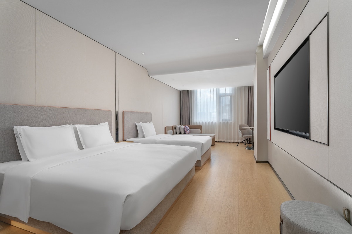 Ett hotellrum med två sängar, en TV och en sittgrupp.