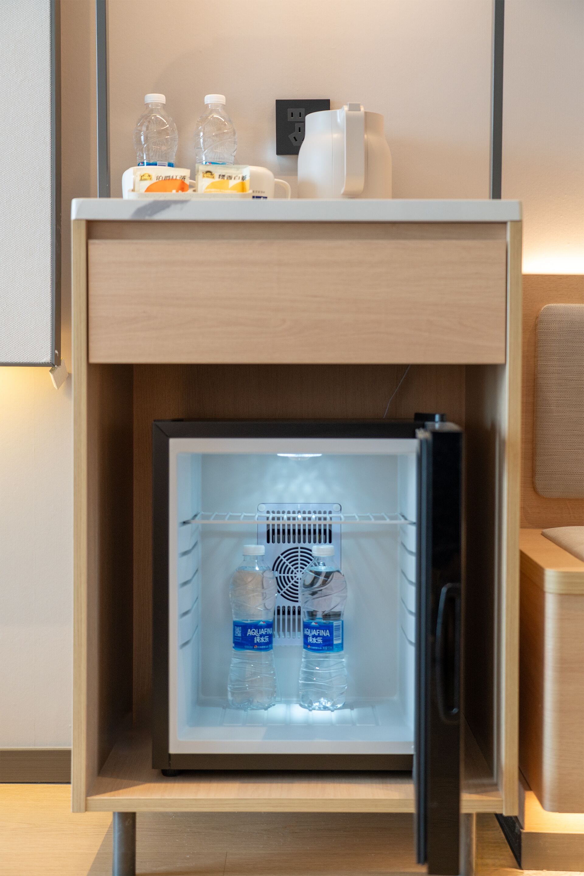 A compact refrigerator with a freezer compartment, containing water bottles and a carton of milk.