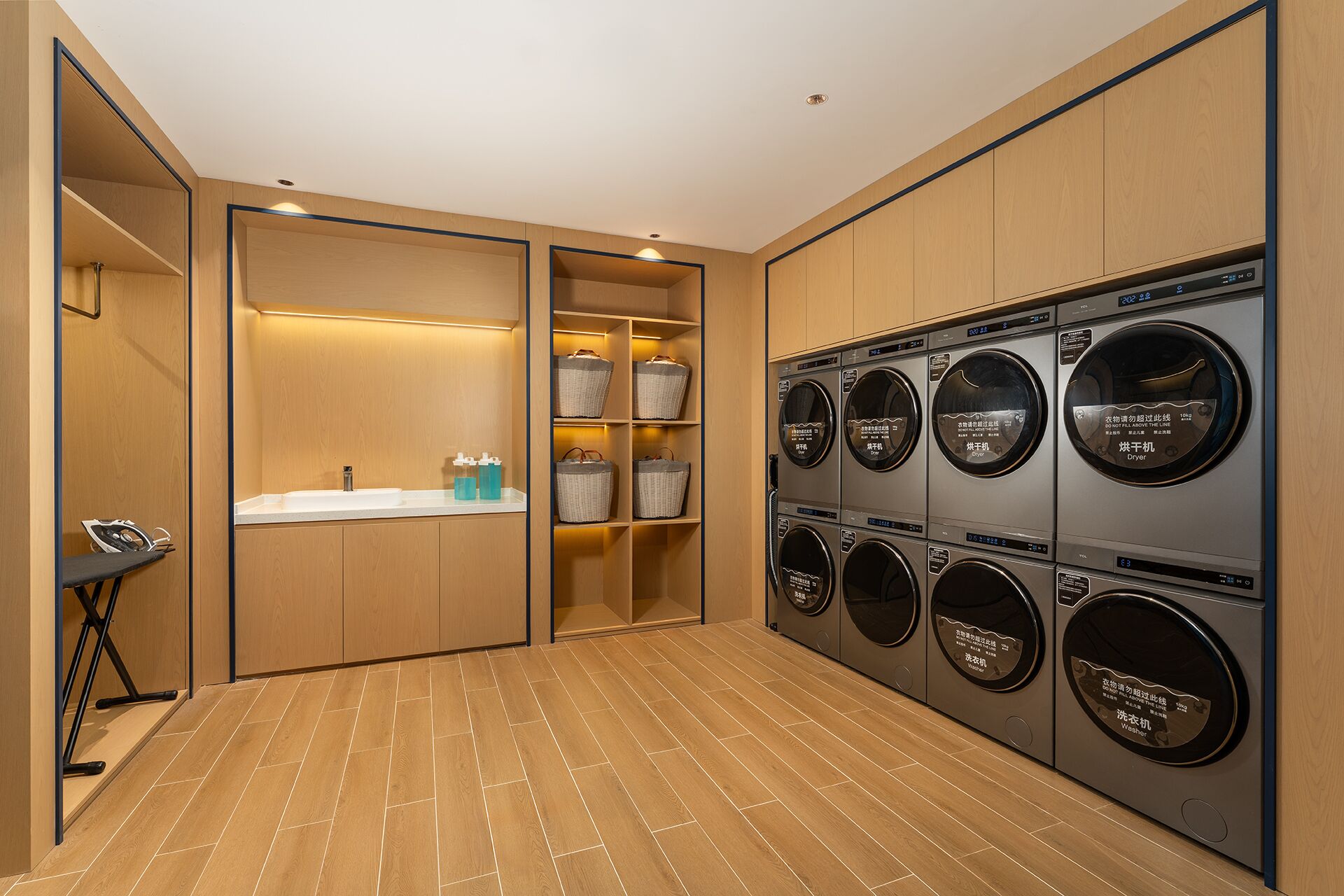 A laundry room with a sink, shelves with baskets, and multiple washing machines.