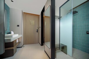 Un bagno moderno con cabina doccia in vetro, una porta in legno e un lavandino bianco con specchio.