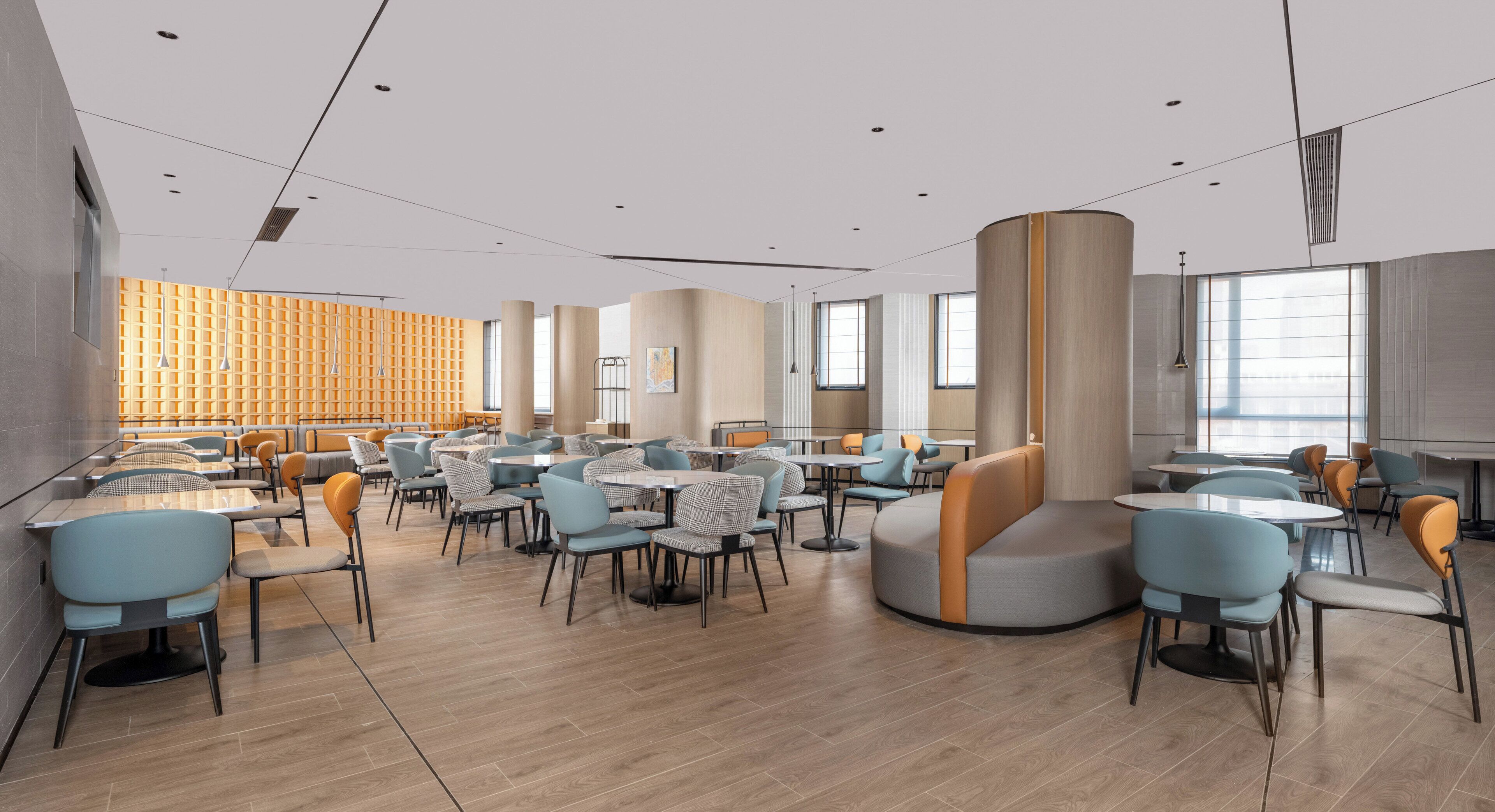 A modern dining area with round tables and chairs, a curved seating area, and large windows providing natural light.