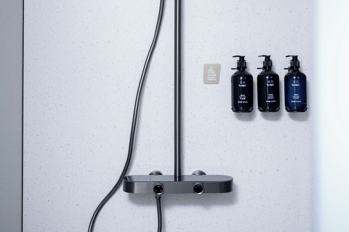 A shower control panel with three bottles of shampoo and conditioner.