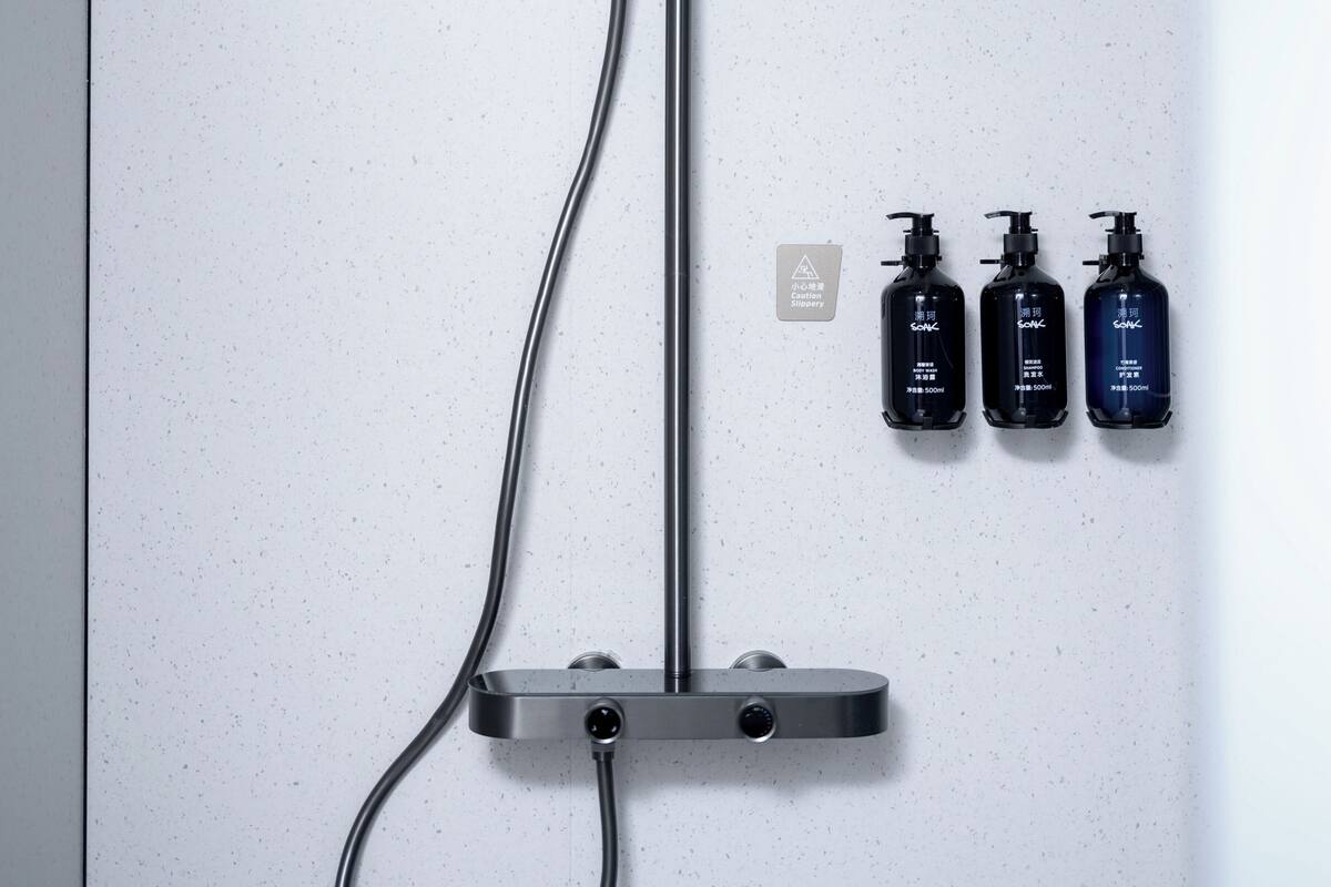 A shower control panel with three bottles of shampoo and conditioner.