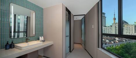 A modern bathroom with a large mirror, a sink, and a view of a cityscape through a large window.