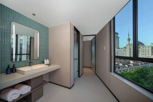 A modern bathroom with a large mirror, a sink, and a view of a cityscape through a large window.