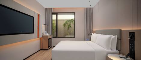 A modern hotel room with a large bed, a bedside table, a TV, and a window with curtains.