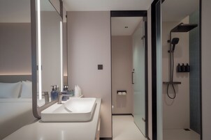 A modern bathroom with a large mirror, a white sink, and a shower area.