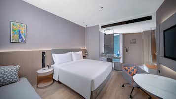 Una habitación de hotel moderna con una cama grande, un escritorio, una silla, un televisor y un baño.