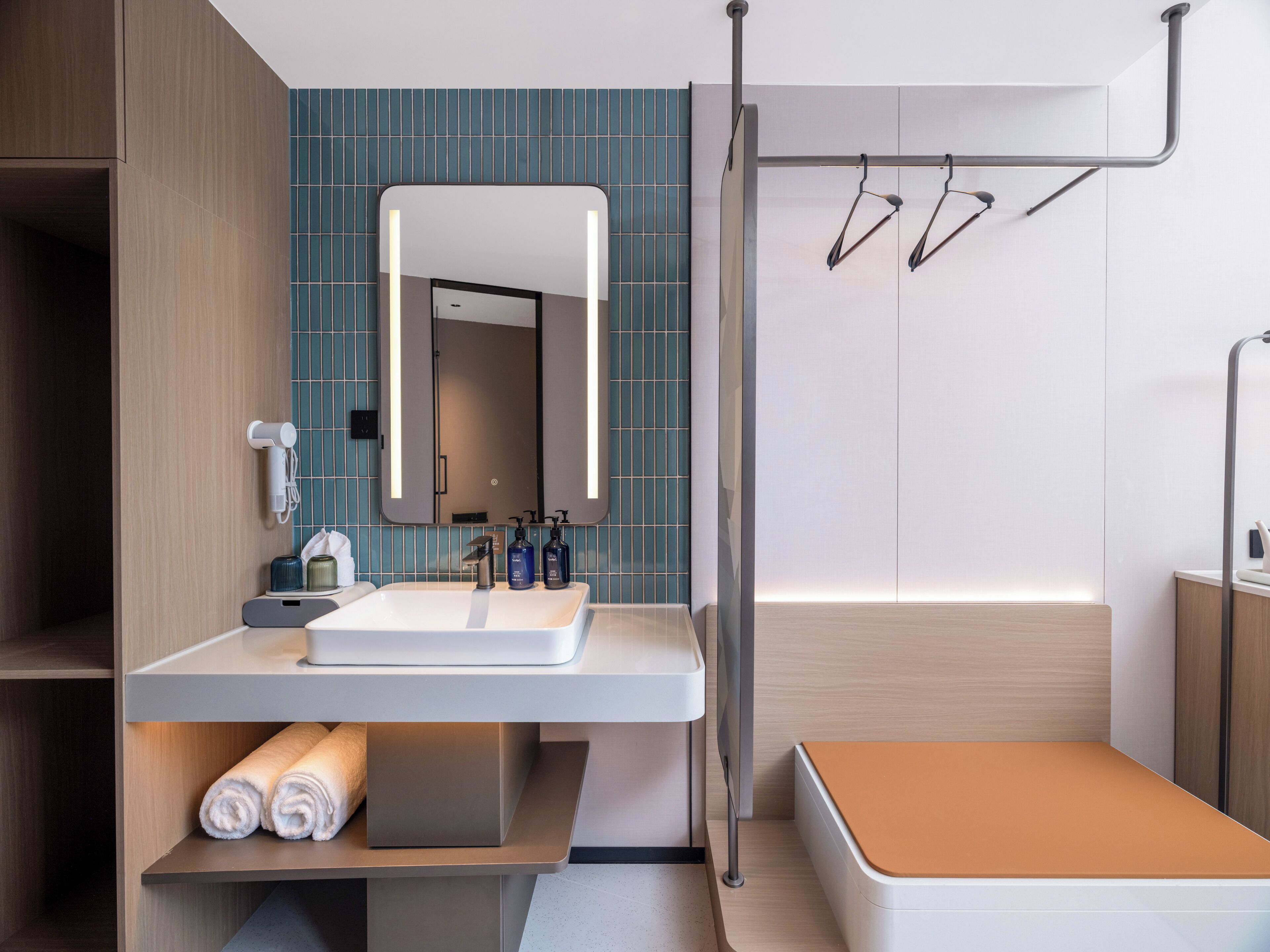 A modern bathroom with a white sink, a large mirror, and a towel rack.