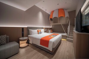 Una habitación de hotel moderna con una cama, un sofá, un televisor y una estructura circular naranja y blanca única.