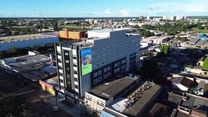 Un edificio de varios pisos con un gran anuncio, un estacionamiento y edificios residenciales y comerciales aledaños.