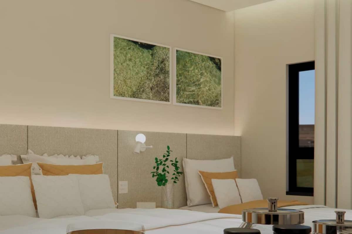 Una habitación de hotel moderna con una cama grande, una mesita de noche y vistas al exterior.