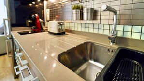 Una cocina moderna con un lavamanos de acero inoxidable, un tostador y un electrodoméstico rojo en la encimera.