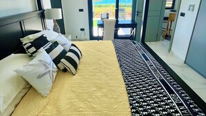 Una camera da letto con un letto, una ventola a soffitto, vista sul mare e una porta che dà su un balcone.