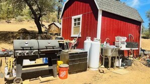 A red wooden structure with a chimney, a barbecue grill, and various containers and tools. - Camping near Sequoia Kings Canyon National Park #8 (Yokuts Valley)