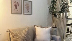 A beige sofa with patterned pillows, a potted plant, and framed botanical illustrations on the wall. - Pousada Estrela do Norte (Tibau do Sul)