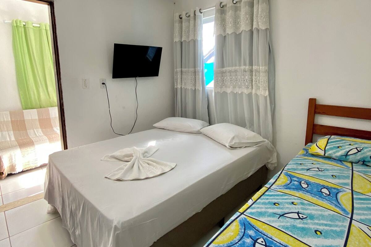 Ein Hotelzimmer mit Bett, Deckenventilator, Fernseher und Klimaanlage.