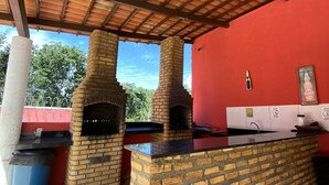 An outdoor kitchen area with two brick ovens, a countertop, and a red wall. - Pousada Estrela do Norte (Tibau do Sul)