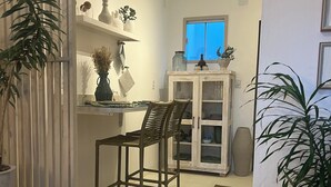 A compact kitchen with a dining area, featuring a wooden chair, a cabinet with glass doors, and a potted plant. - Pousada Estrela do Norte (Tibau do Sul)