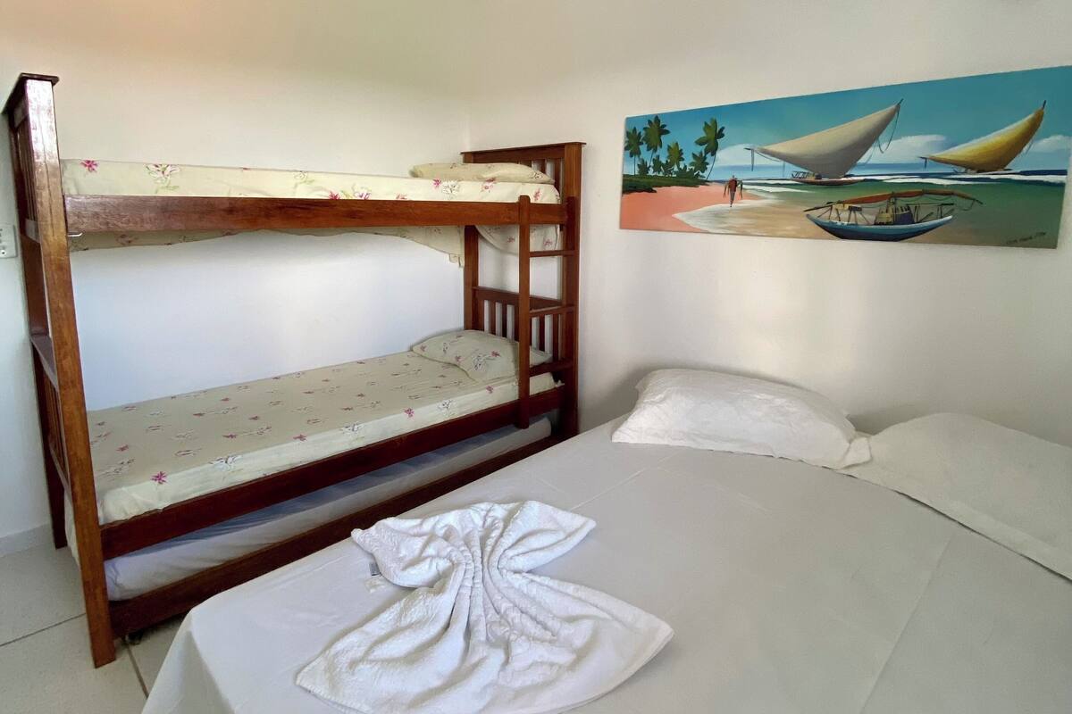 Ein Zimmer mit Etagenbetten, Deckenventilator, Klimaanlage und einem Wandbild mit Booten.