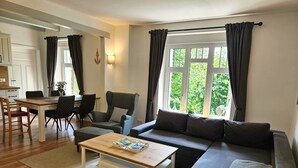 A modern living room with a sofa, a coffee table, and a dining area with chairs and a table.