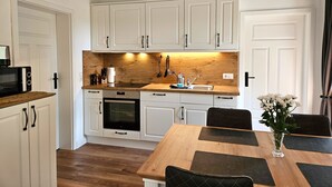 A modern kitchen with white cabinets, a wooden countertop, a built-in oven, and a dining table with black placemats.