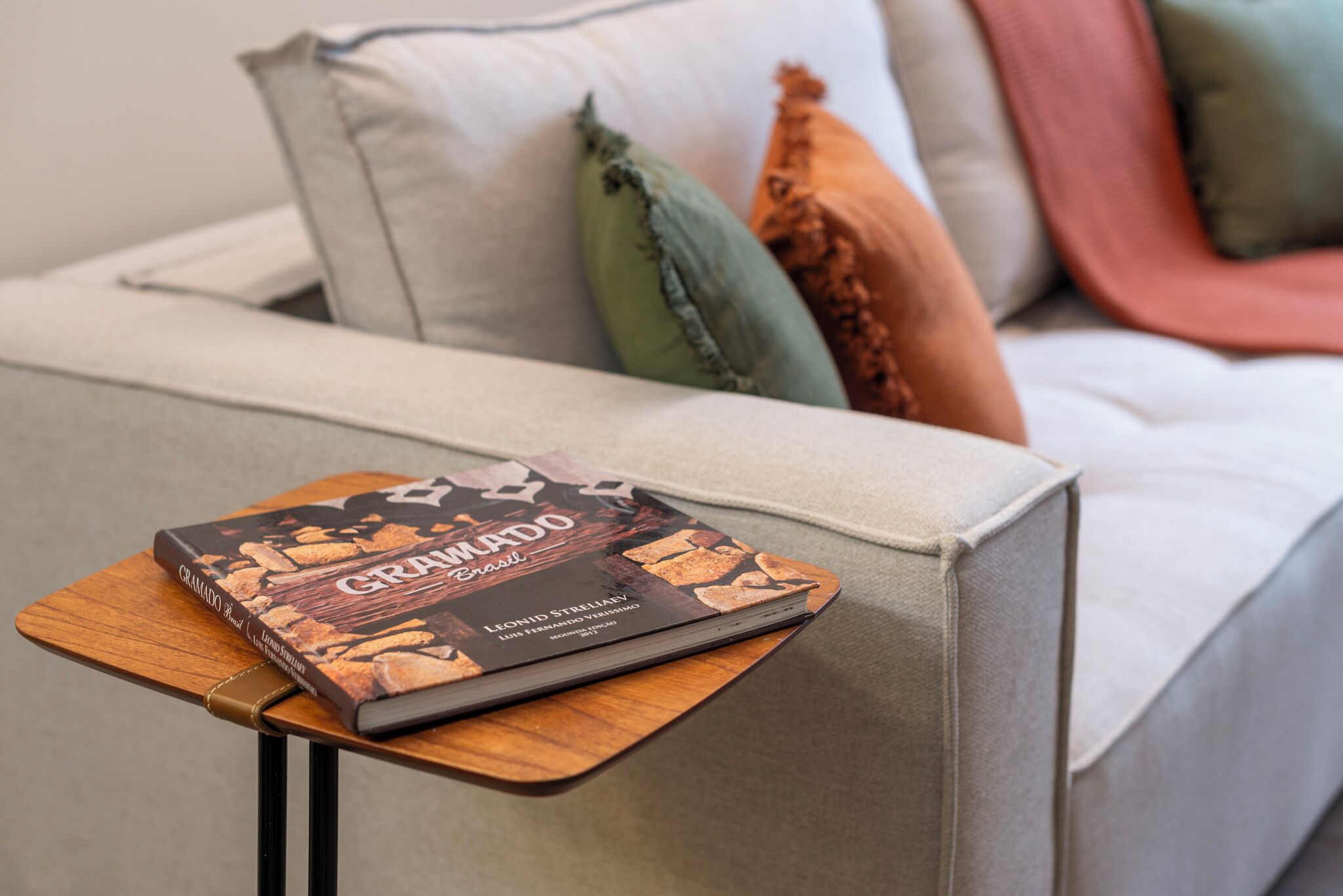 Un livre intitulé « Crawford Brazil » est posé sur une petite table en bois, à côté d’un canapé agrémenté de plusieurs coussins.