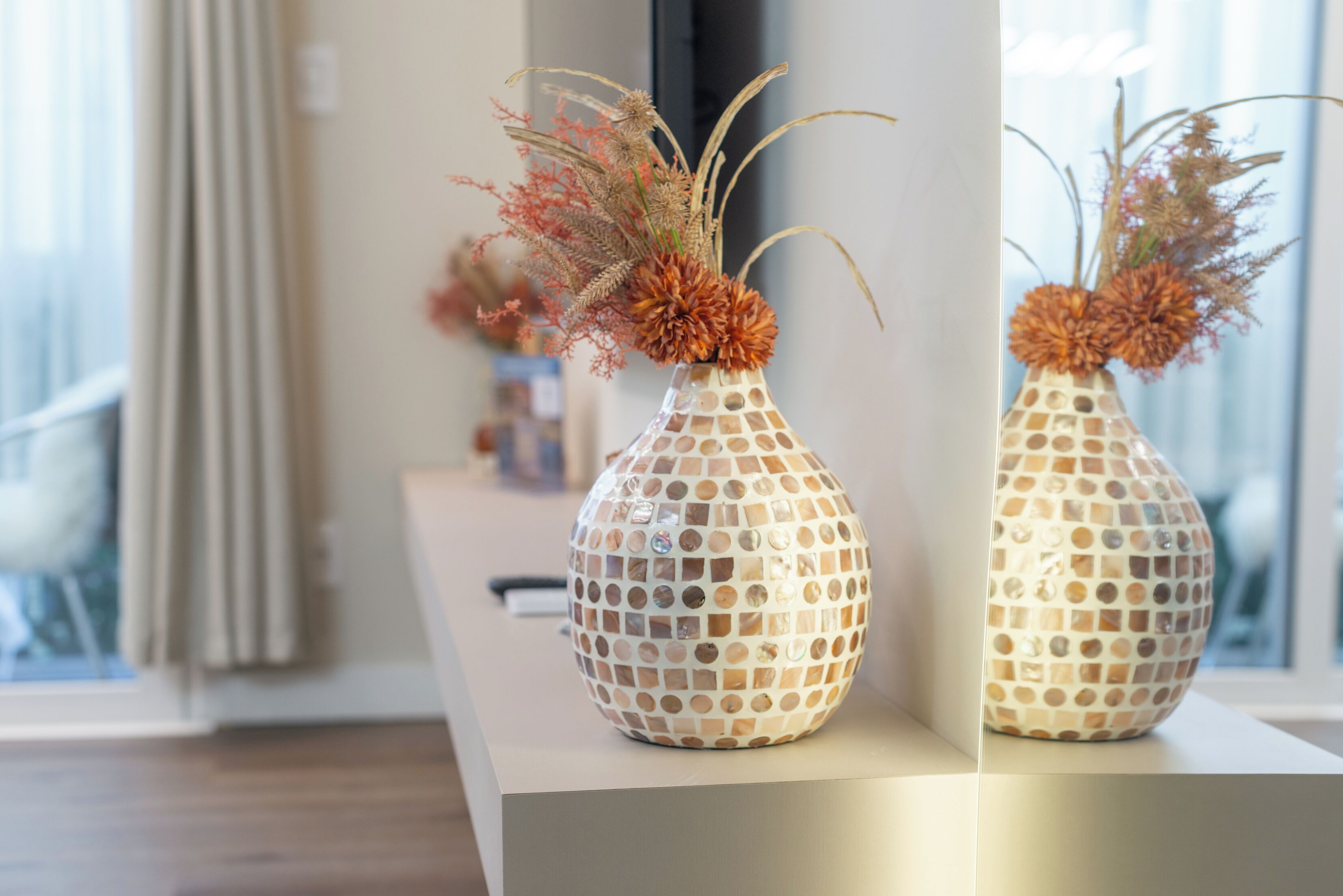Two decorative vases with a mosaic pattern on a table.