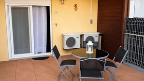 A patio with a table and chairs, an air conditioning unit, a lantern, and a sliding glass door.