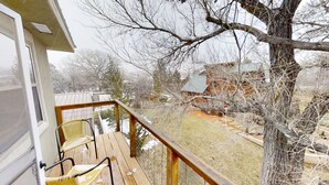 A wooden deck with two chairs, a view of a snowy landscape, and a tree in the foreground. - Hidden Get Away (Silver City)