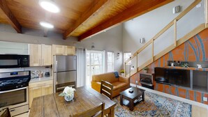 A compact kitchen with modern appliances, a dining area with a wooden table and chairs, and a cozy living space with a sofa and a fireplace. - Hidden Get Away (Silver City)