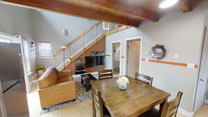 A dining area with a wooden table and chairs, a sofa, and a staircase leading to an upper level. - Hidden Get Away (Silver City)