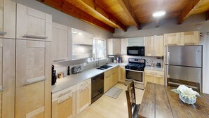 A modern kitchen with wooden cabinets, a stainless steel refrigerator, a microwave, and a stove. - Hidden Get Away (Silver City)