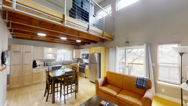A spacious kitchen with wooden beams, a dining area with a table and chairs, and a living room with a sofa. - Hidden Get Away (Silver City)