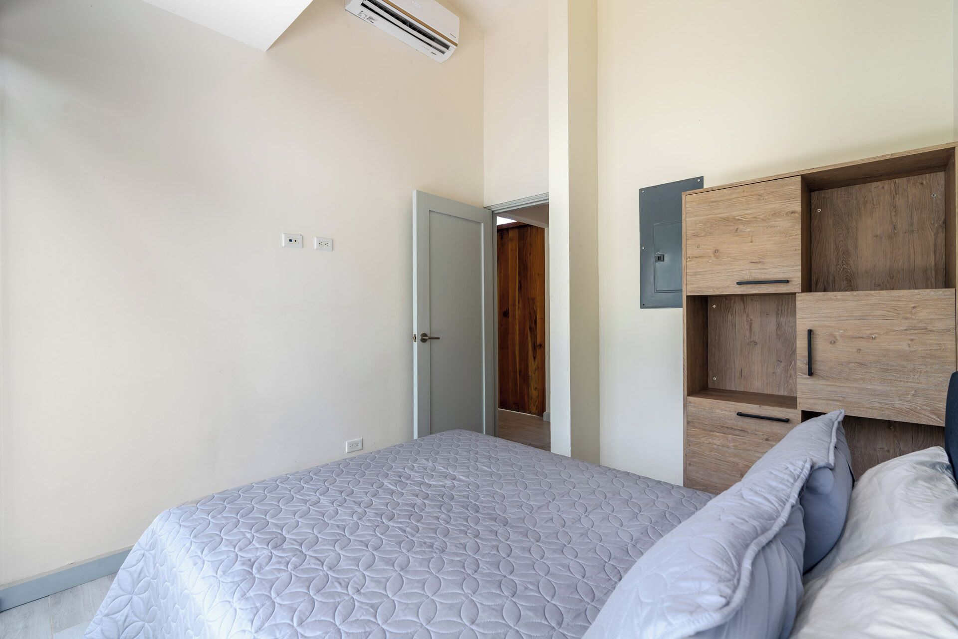 Une chambre à coucher avec un lit, une armoire en bois et une porte donnant sur une autre pièce.