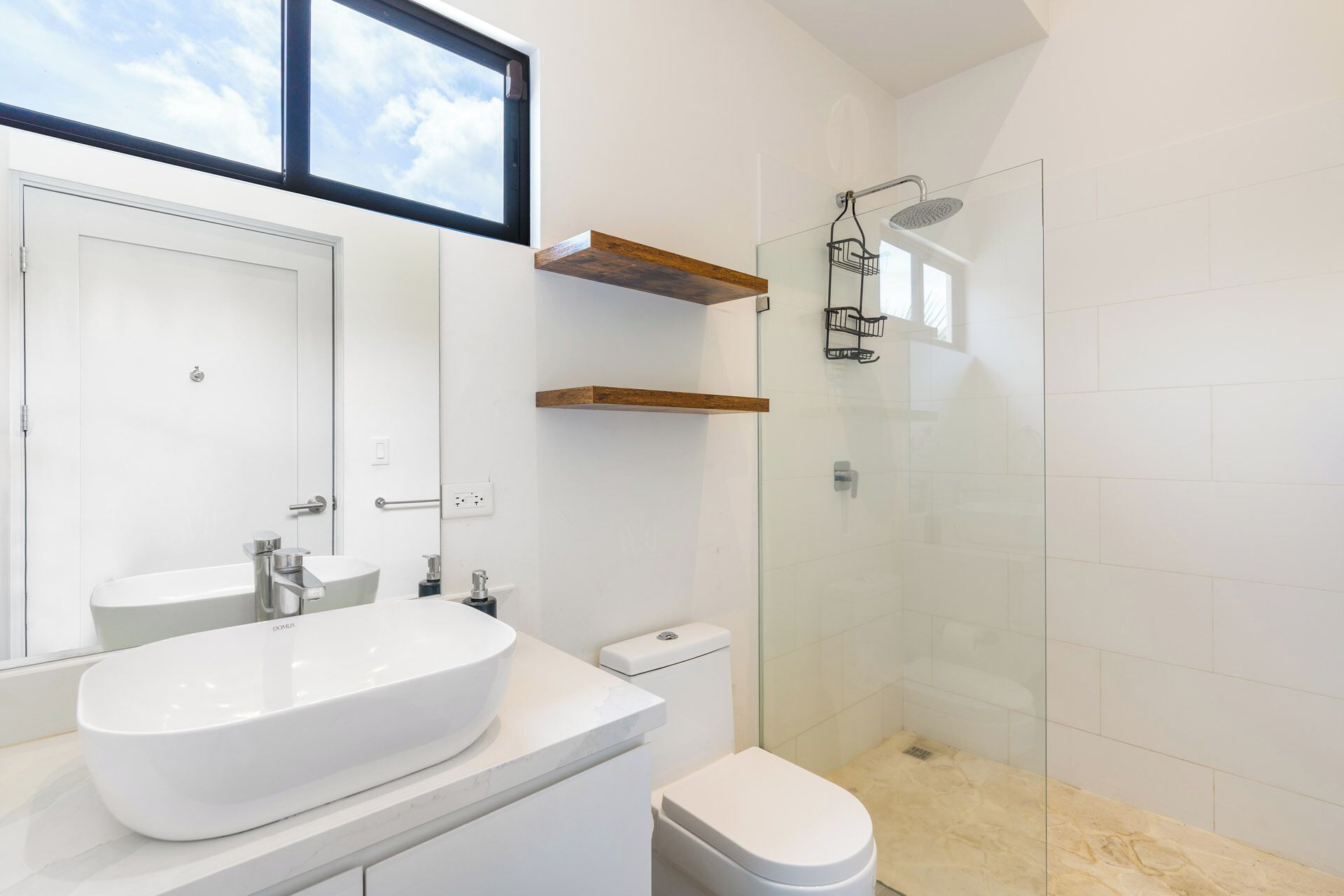Une salle de bain moderne avec un lavabo blanc, des toilettes et une douche à parois de verre.