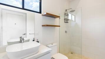 Une salle de bain moderne avec un lavabo blanc, des toilettes et une douche à parois de verre.