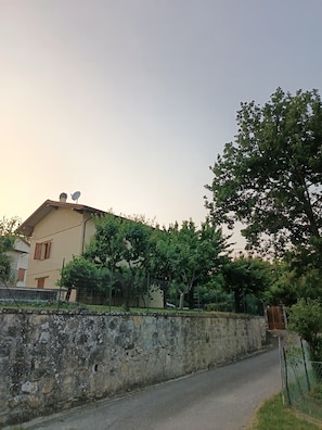 Un bâtiment avec un mur en pierre, une route pavée et des arbres.