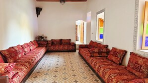 Une pièce avec deux canapés rouges à motifs, un sol à motifs et un plafond en bois.