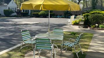 A patio with a yellow umbrella, metal chairs, and a table.