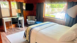 A bedroom with a bed, a desk, a chair, a television, and a window with curtains. - Cape Cod Motor Inn (South Yarmouth)