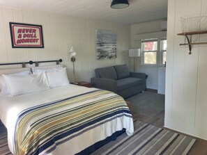 A bedroom with a bed, a gray sofa, a framed motivational quote, and a window. - Cape Cod Motor Inn (South Yarmouth)