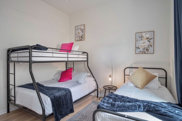 Une chambre de dortoir avec des lits superposés, une table de chevet avec une lampe et des œuvres d’art florales accrochées aux murs.